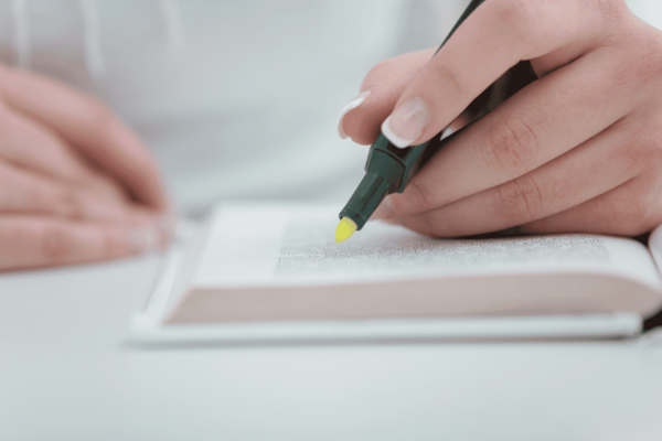 A beta reader writes in a book with a pen, focusing intently on their task.